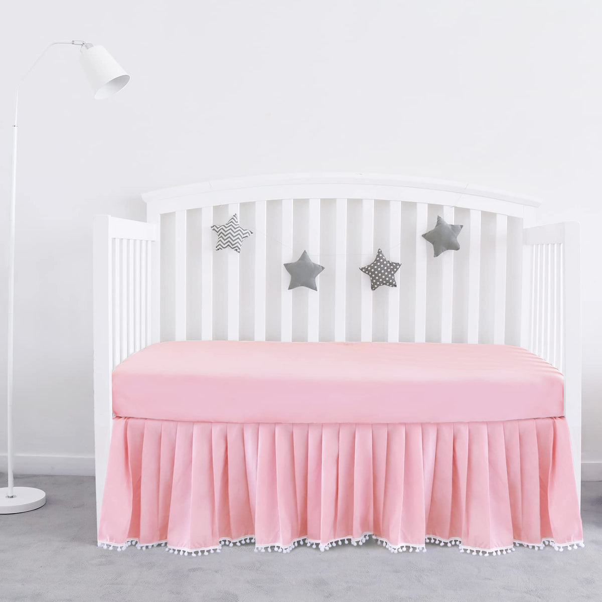 Biloban pink crib skirt pleated with pompoms enhances crib decor and tidy under-bed space