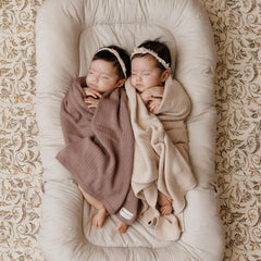 Bleu La La swaddle blanket draped on a crib, soft oatmeal shade.