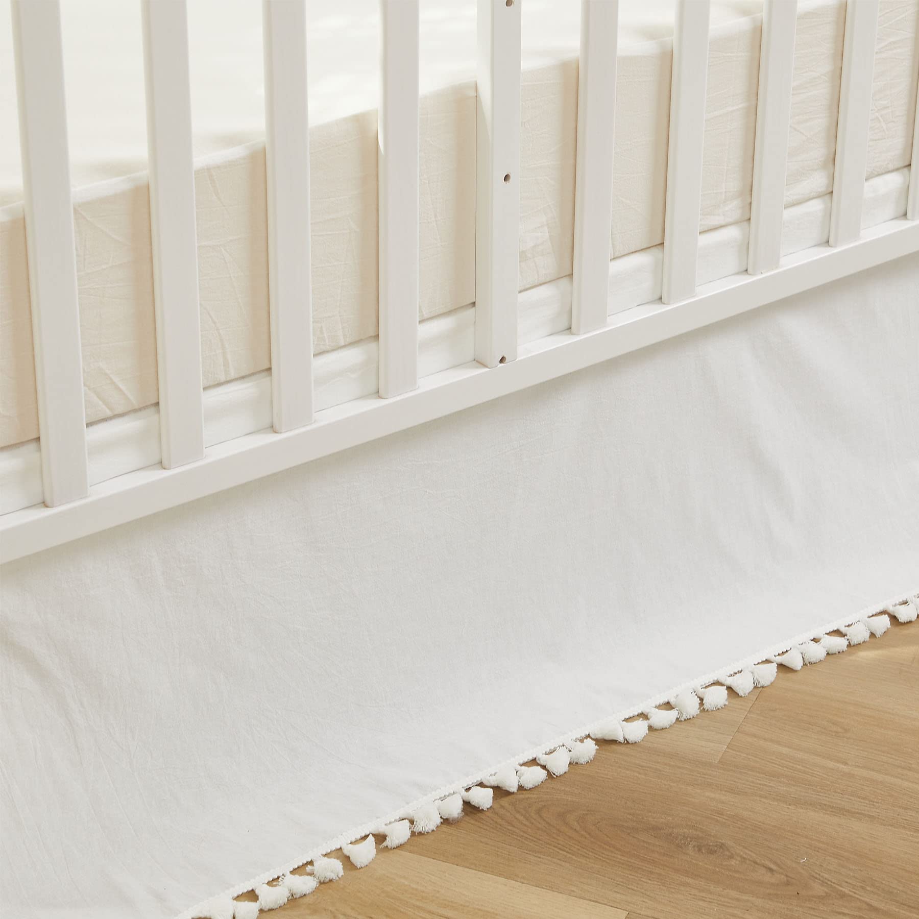 Brandream crib skirt in cream with tassel fringe enhances neutral nursery decor.