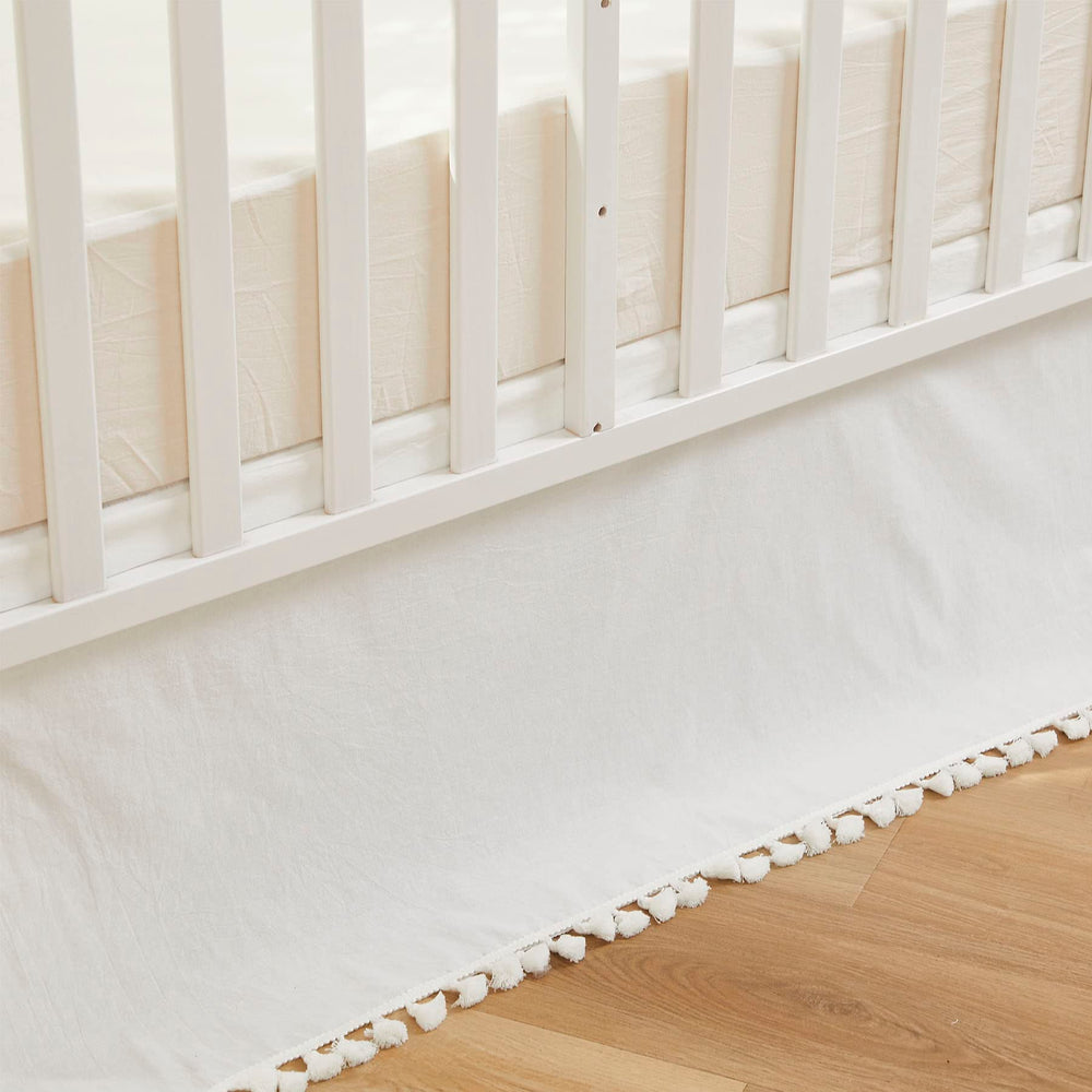 Brandream crib skirt in cream with tassel fringe enhances neutral nursery decor.