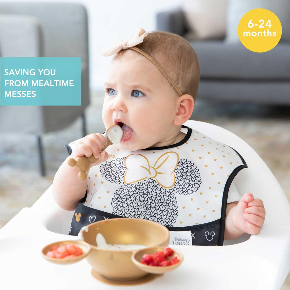 Bumkins bib shows crumb catcher pocket catching spills during self-feeding.