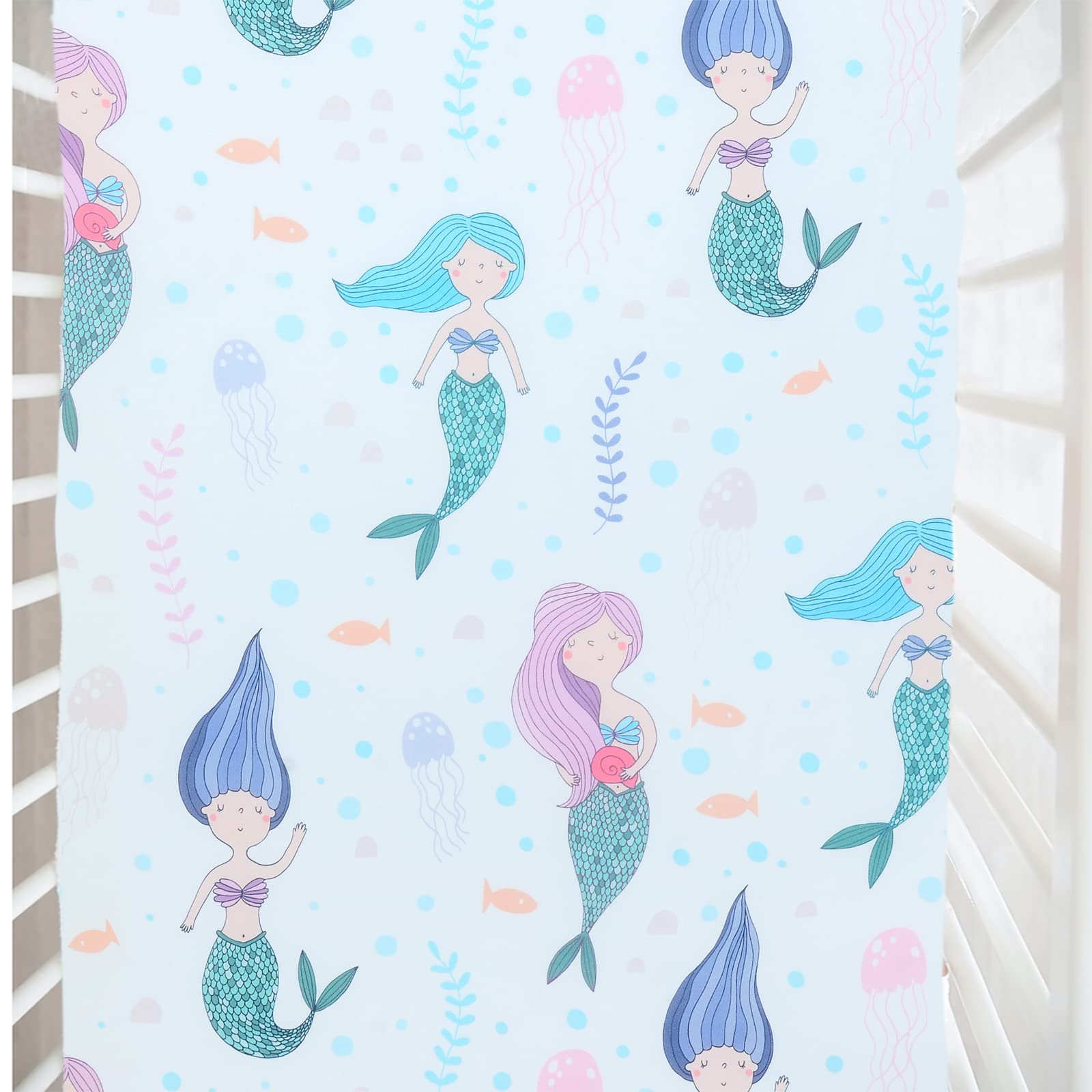 Cloele Mermaids crib sheet in top view showing snug standard-crib fit.