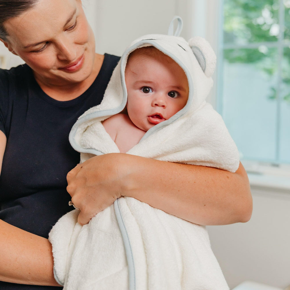 Copper Pearl Juno hooded towel displayed in a cozy nursery setup.