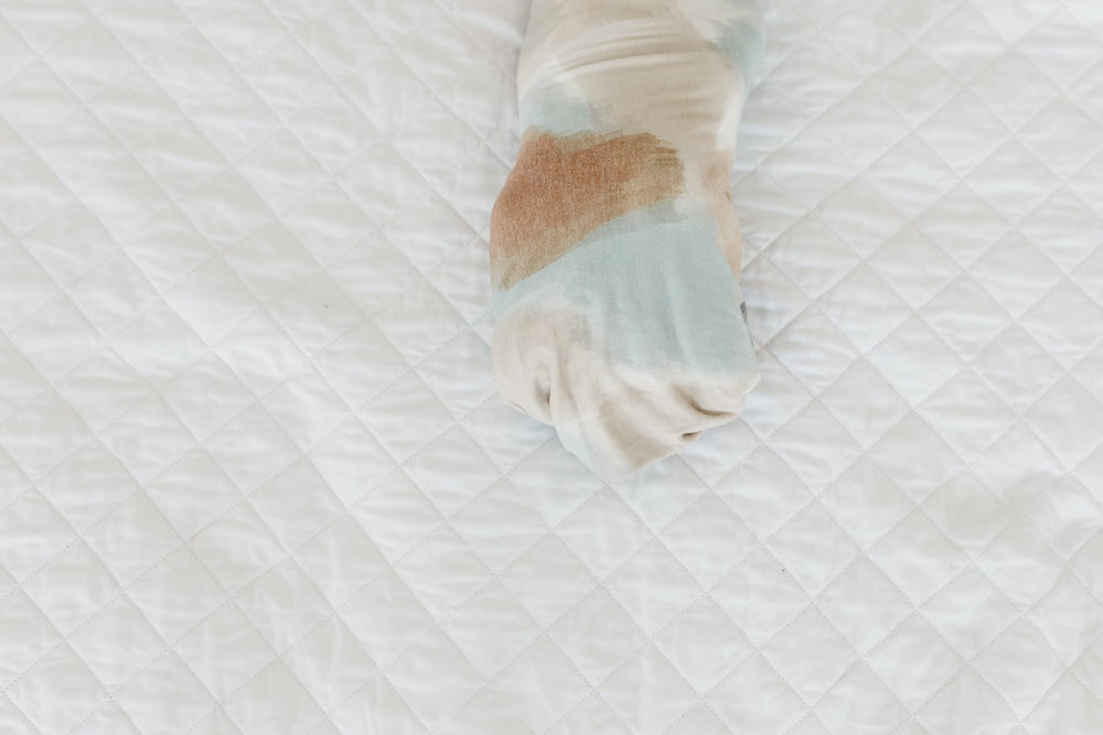 Copper Pearl Picasso large swaddle blanket being used as a light baby cover
