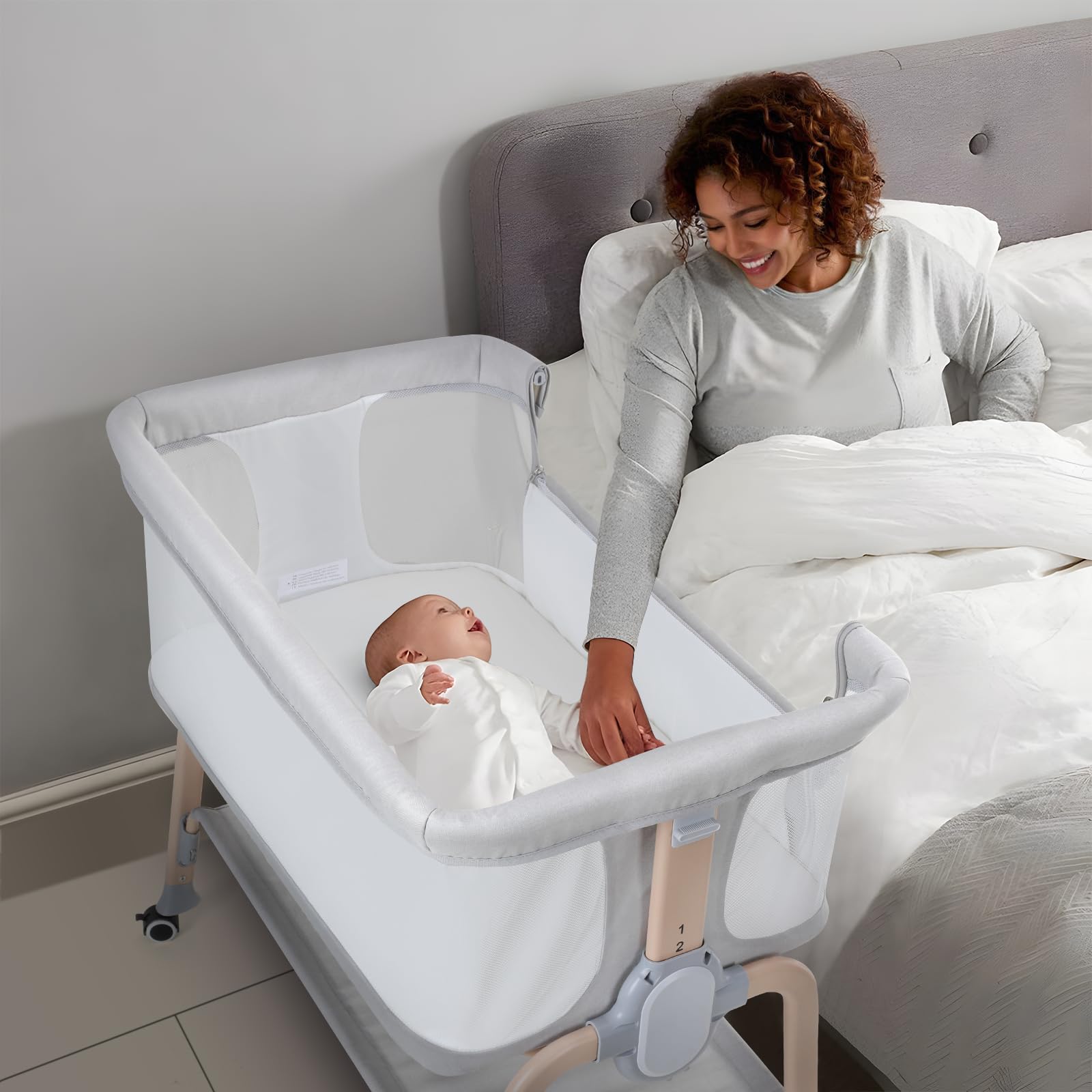 Cowiewie bassinet bedside sleeper in light grey finish beside a parent for nighttime check-ins.