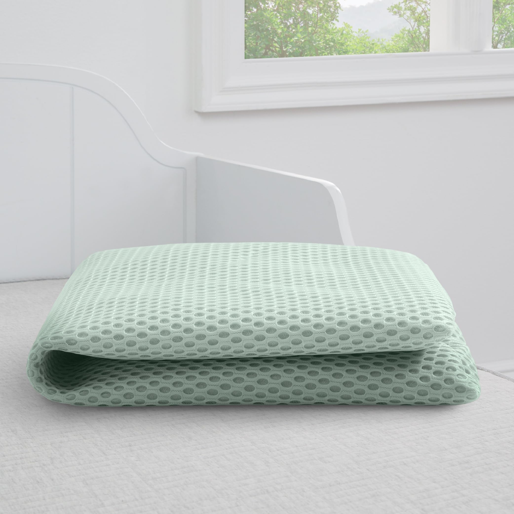 Delta Children breathable crib mattress pad cover on a crib demonstrates universal fit