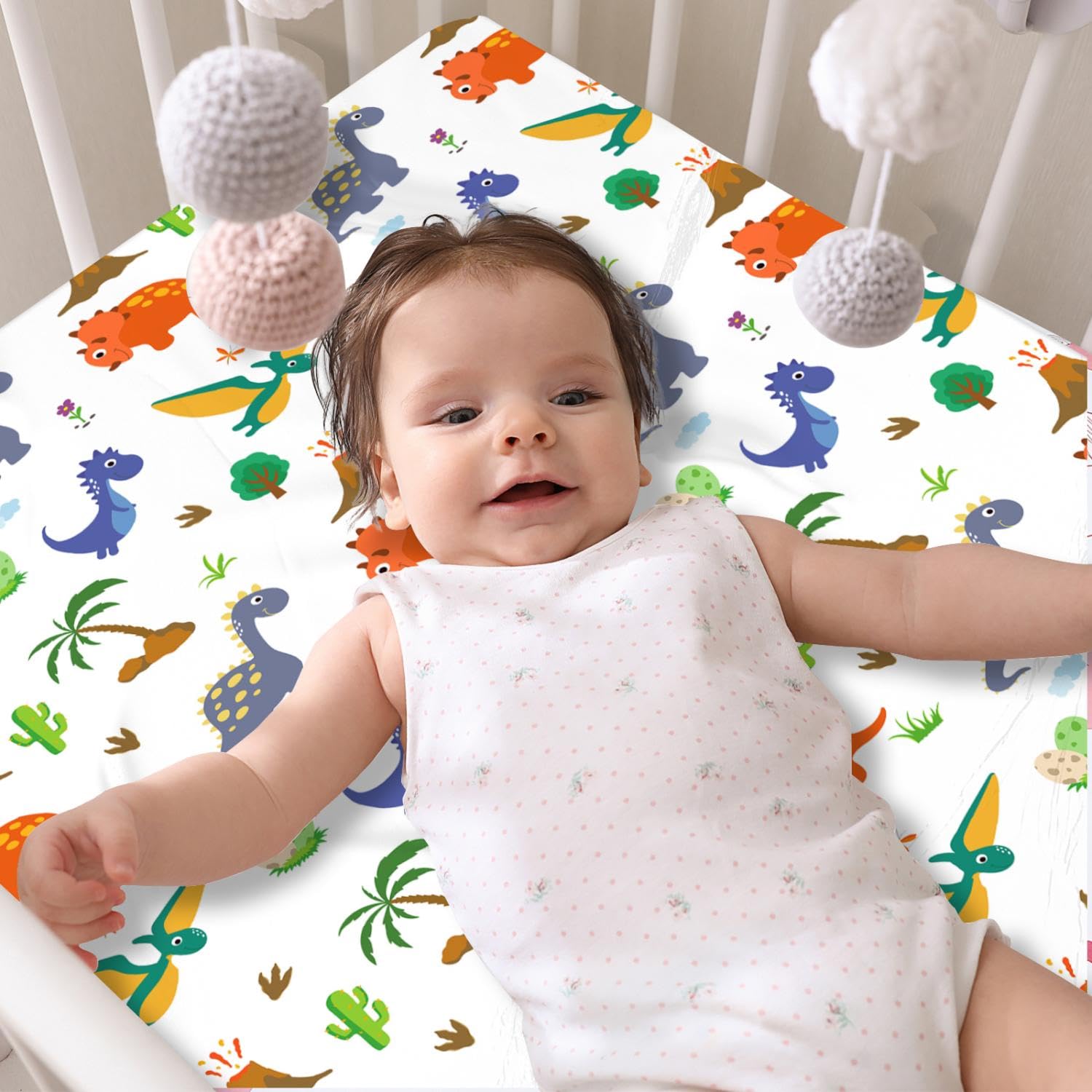 DengFengLai dinosaur crib sheet four-pack laid out, vibrant patterns brighten nursery.