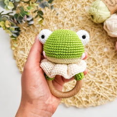 DICHA wood baby rattle held by tiny hands for scale.