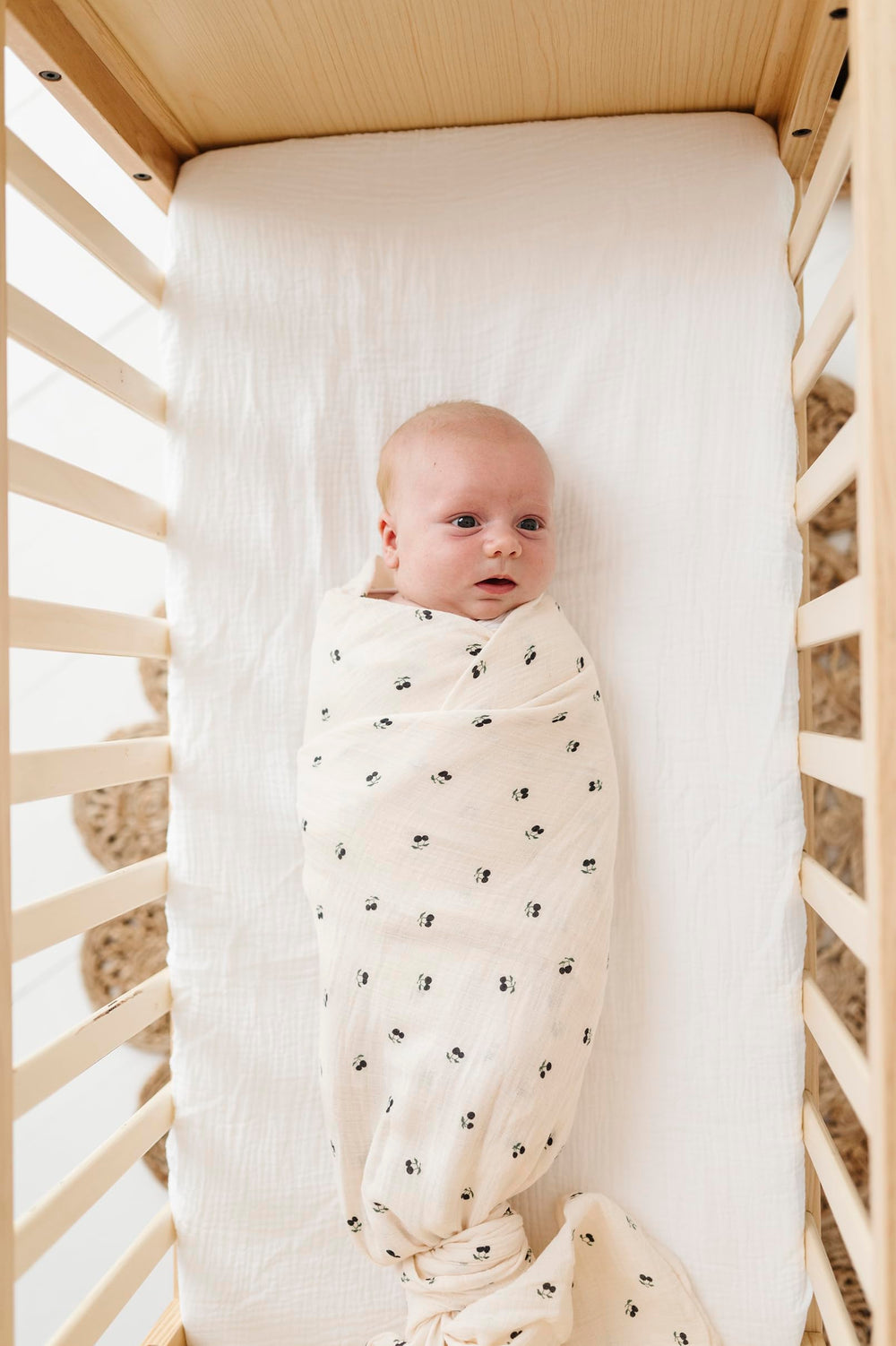 Blue cherry print swaddle blanket by Ely's & Co. shown folded and ready to use