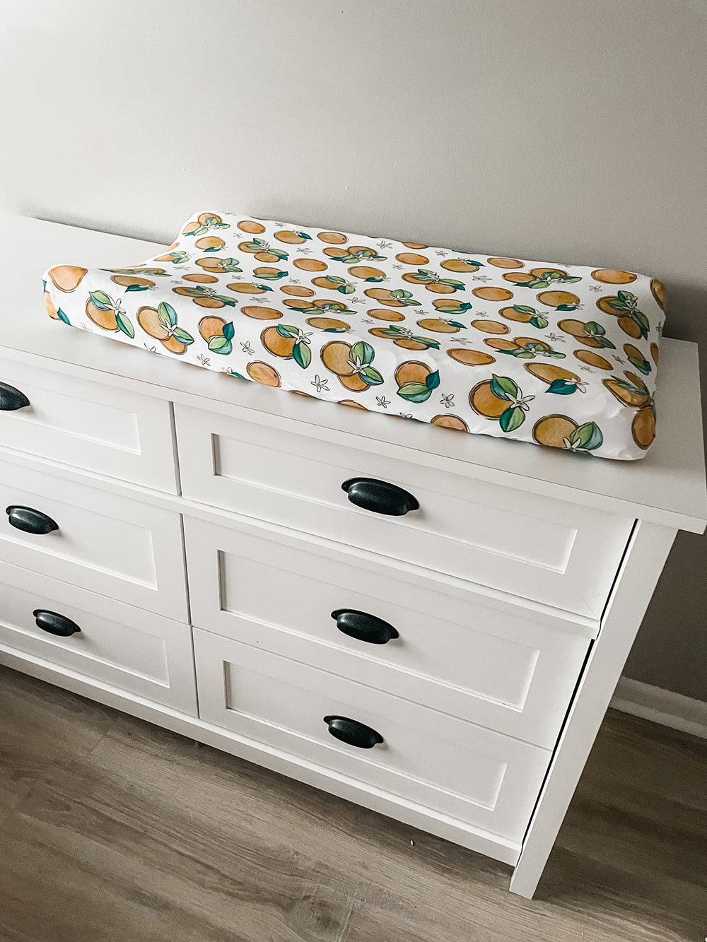 Florida Kid Co. Orange Blossom fitted cover on a changing pad promotes quick cleanup after messes.
