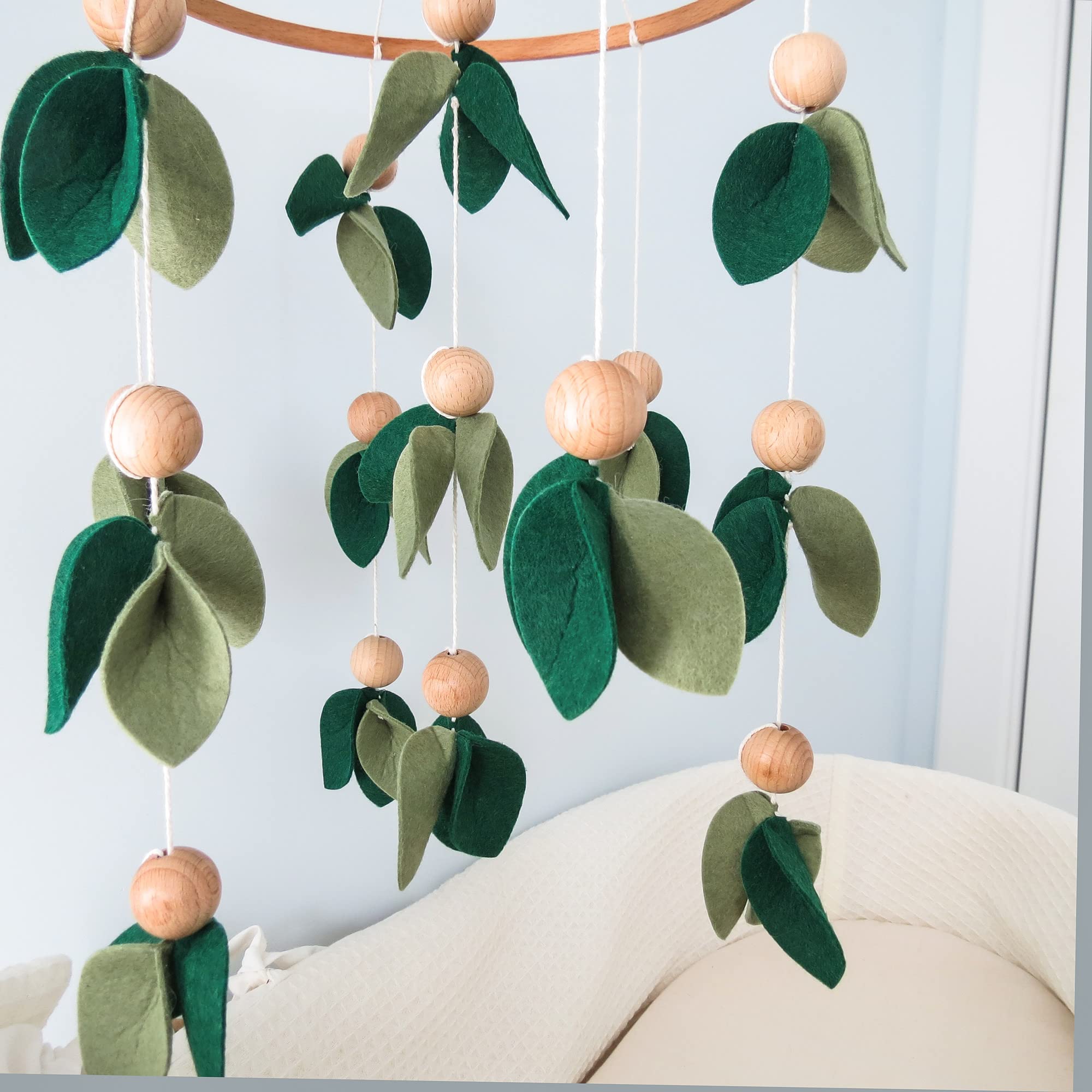 Goukurlsma dark green leaf bead mobile enhances calm nursery aesthetics.