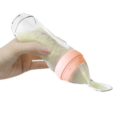Haakaa silicone baby food dispensing spoon showing peach lid and tube for mess-free feeds.