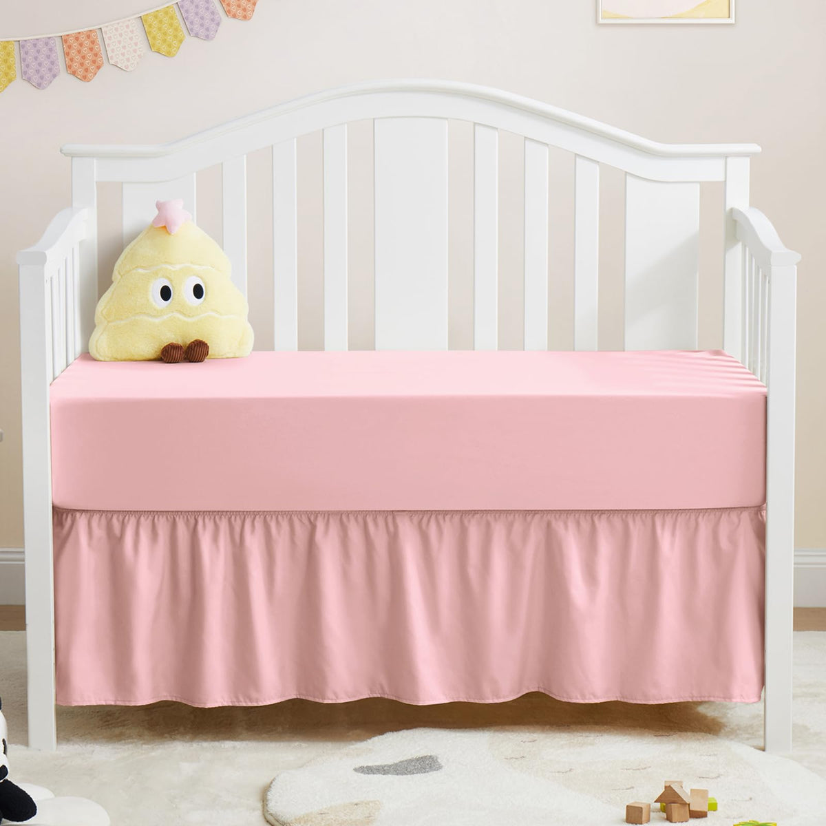 Horbaunal pink crib skirt and sheet set shown together for a coordinated nursery look.