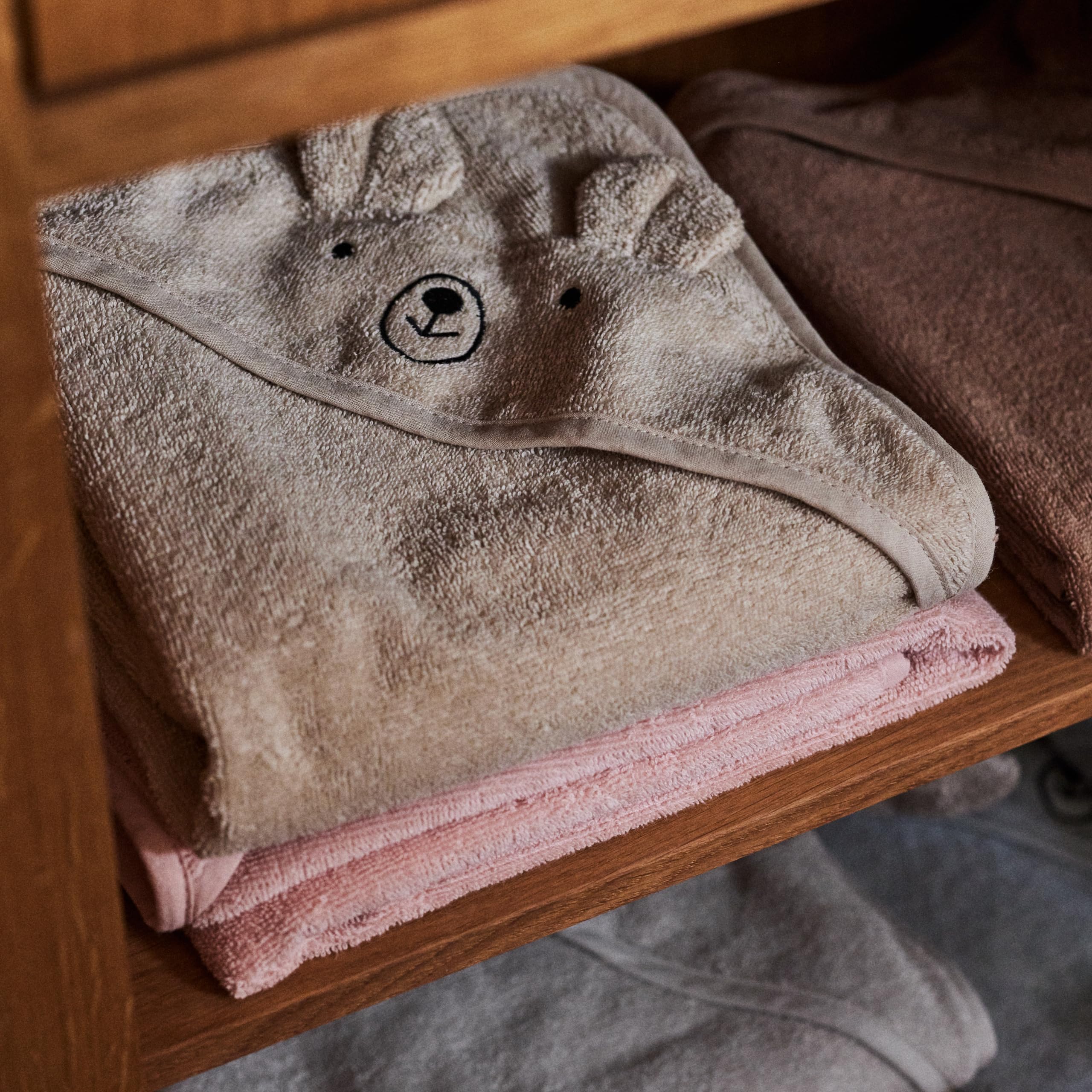 Huxie towel in bathroom scene with baby, suggesting cozy bath or beach use.