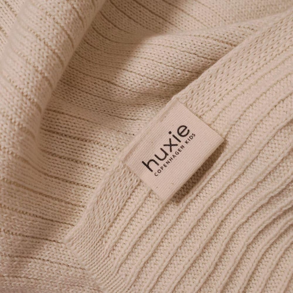 Huxie knitted baby blanket in arms for soothing comfort.