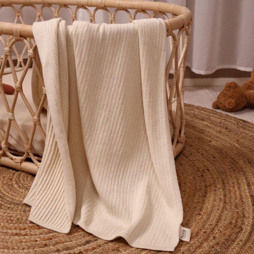 Huxie knitted baby blanket in car seat offers cozy travel.