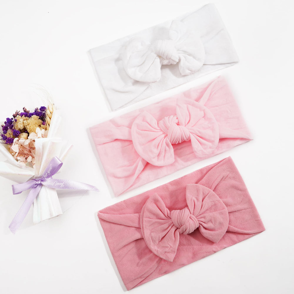 Kangaroo adjustable baby bow headband demonstrates easy self tie for a custom fit.