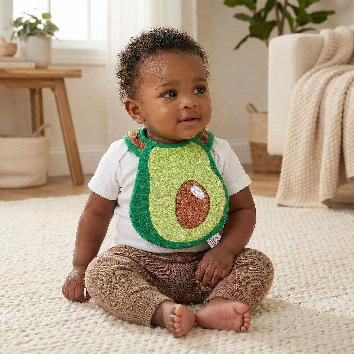 Keiki Care avocado-shaped bib with adjustable snaps for growing babies.
