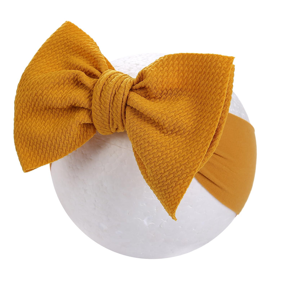 KIDOCHEESE Big Bows stretched headband demonstrating flexible sizing.