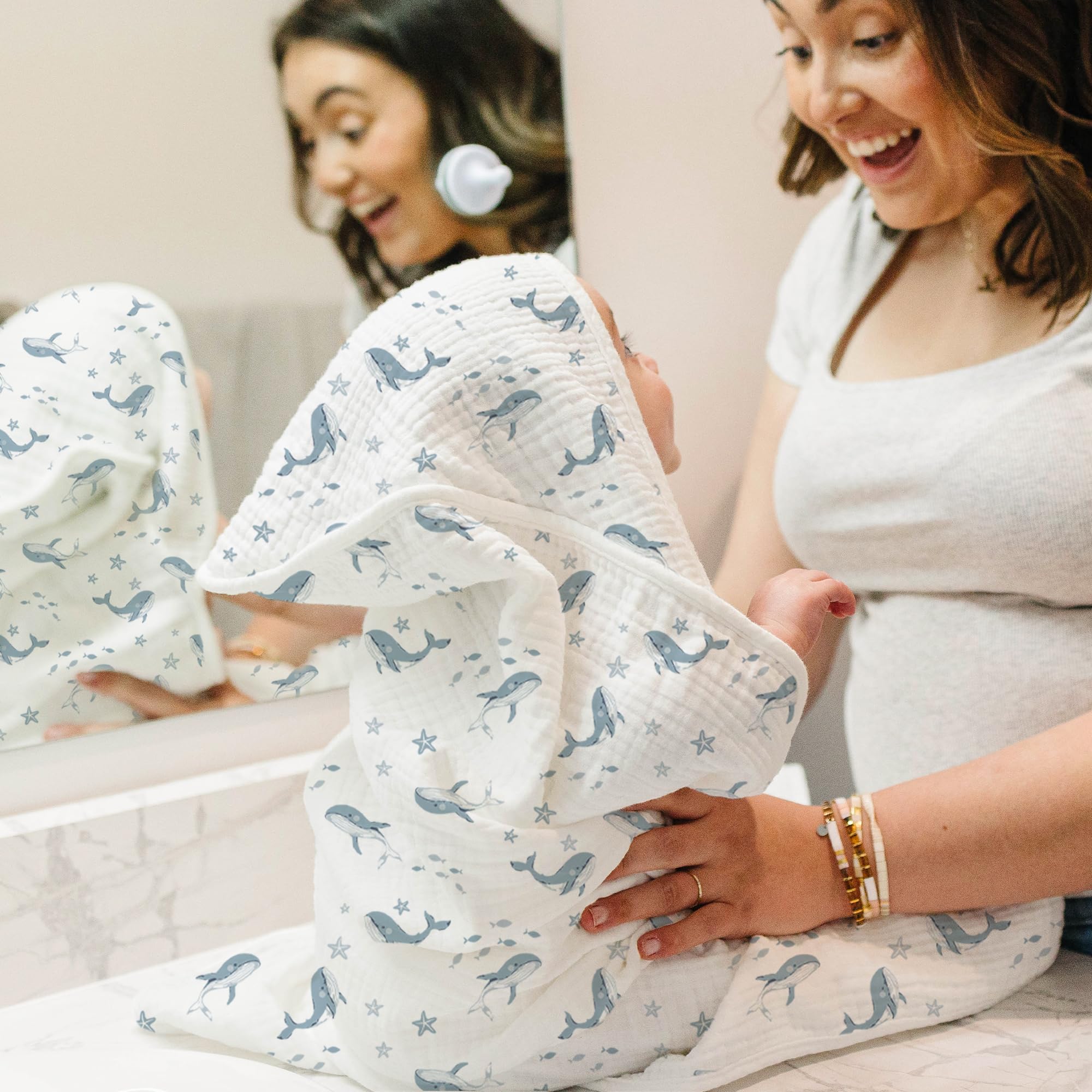 Konssy blue whale hooded towel draped over head to keep baby cozy.