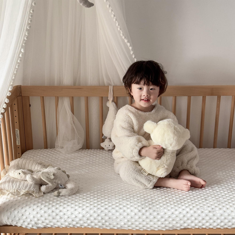 La Sheer fuzzy crib sheets — elastic banding visible for secure, slip-free fit.