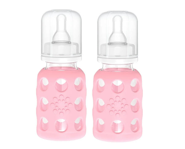 Lifefactory pink silicone sleeve on glass baby bottle for secure grip during feeding.