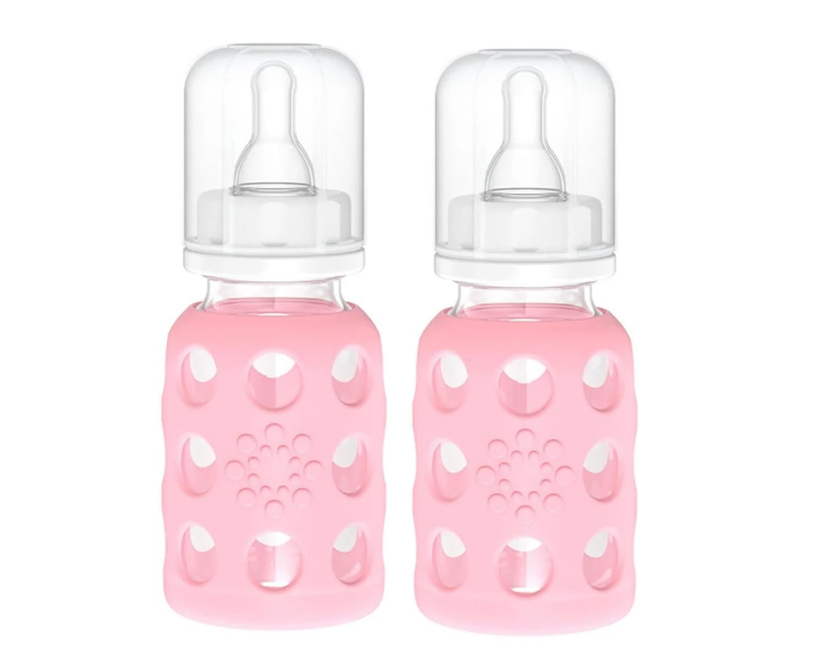 Lifefactory pink silicone sleeve on glass baby bottle for secure grip during feeding.