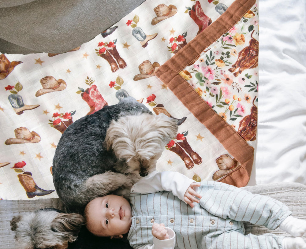 Little Jump cowgirl floral Highlandcow muslin blanket draped over crib for cozy days.