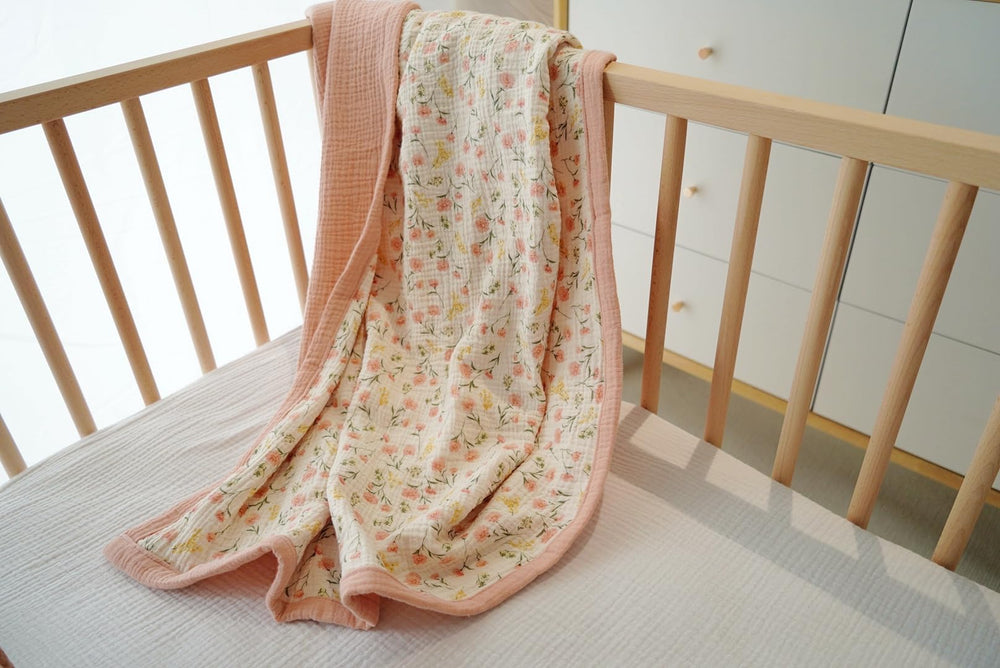 Little Jump peach floral blanket on crib demonstrates lightweight, breathable material ideal for warm days.