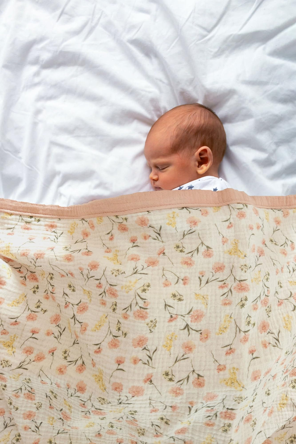 Little Jump muslin blanket in nursery setup highlights charming boho pink floral design.