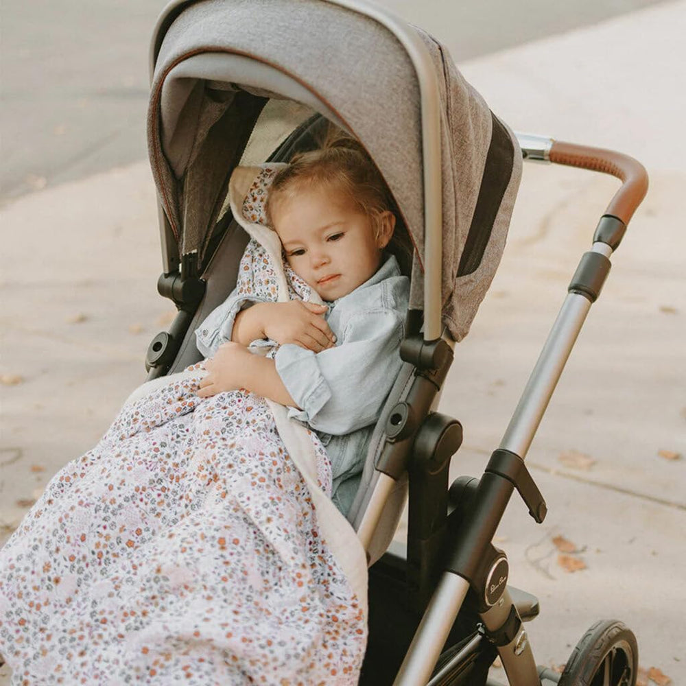 Little Unicorn newborn quilt in use as a cozy travel cover for naps.