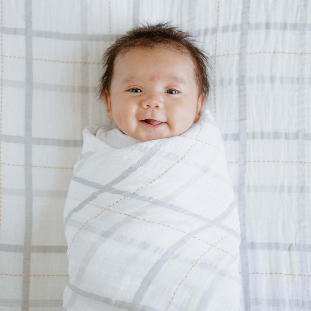 Little Unicorn grey plaid blanket styled in a cozy nursery setting