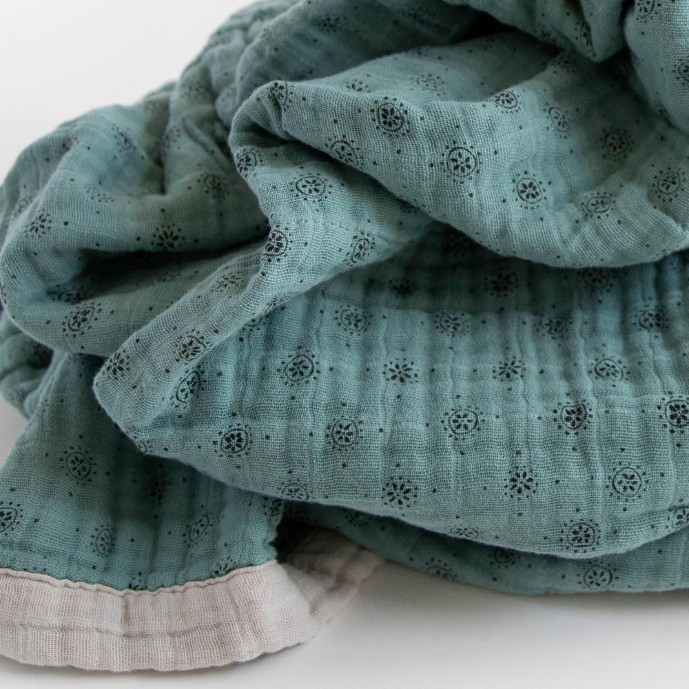 Little Unicorn premium quilted throw serving as a car seat wrap for travel comfort.