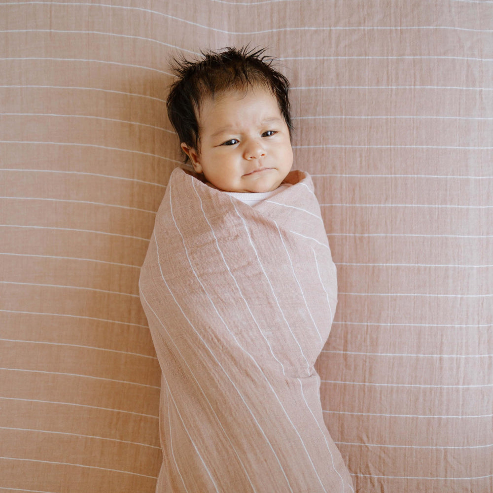 Little Unicorn Mauve Stripe swaddle used as burp cloth during feeding.