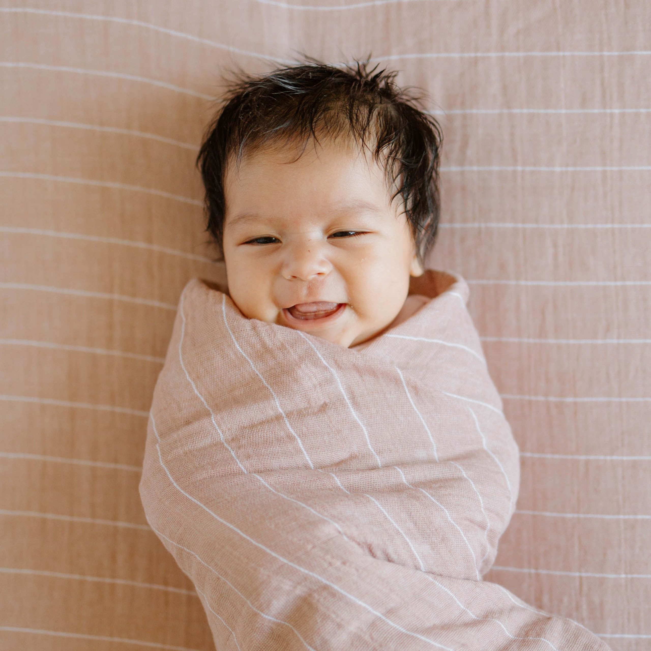 Little Unicorn Mauve Stripe swaddle being machine washed for easy care.
