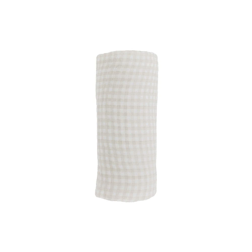 Little Unicorn tan gingham swaddle on baby for secure, comfortable rest.