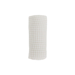 Little Unicorn tan gingham swaddle on baby for secure, comfortable rest.