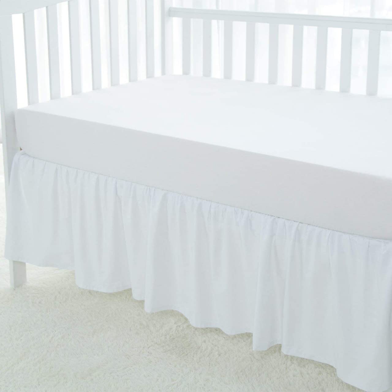 Love2Sleep dust ruffle on mini crib demonstrates secure fit and elegant white finish