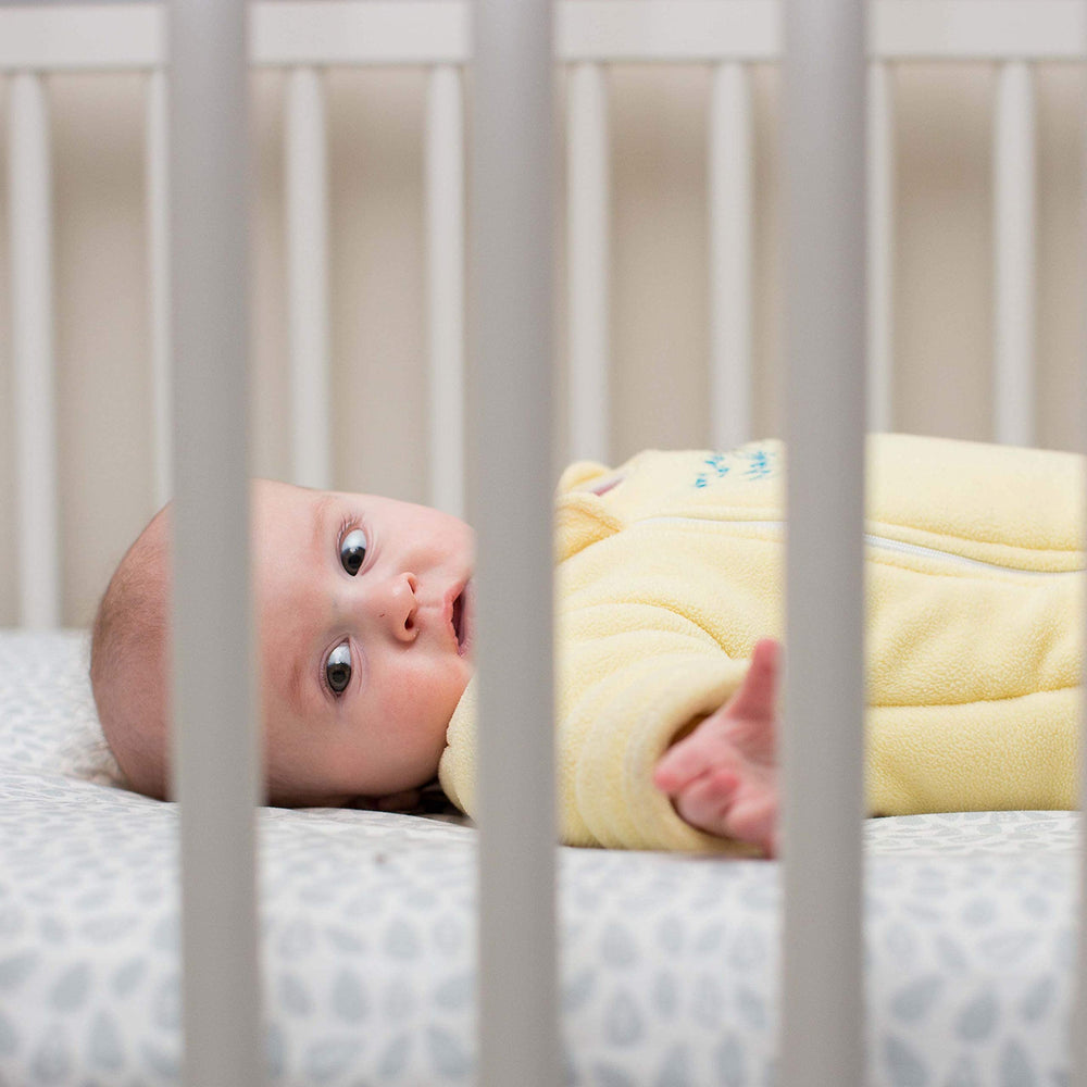Magic Sleepsuit in a bare crib promoting back sleeping with cozy insulating layer.