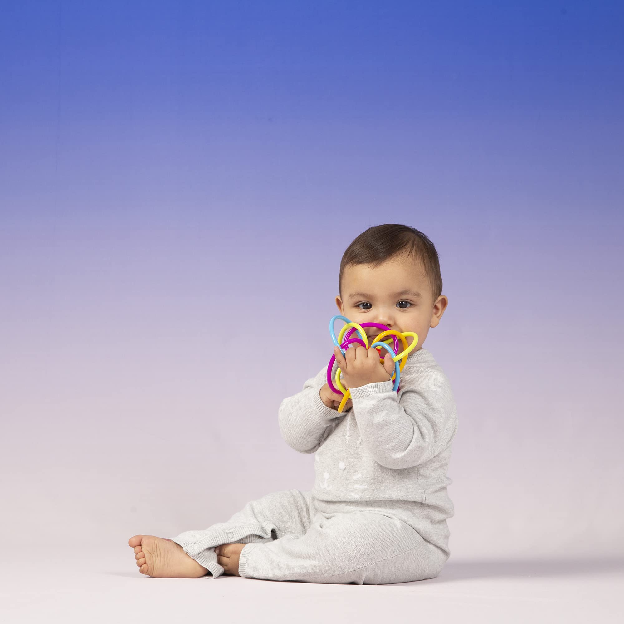 Baby grasps Winkel with two-handed play in a small, portable toy.