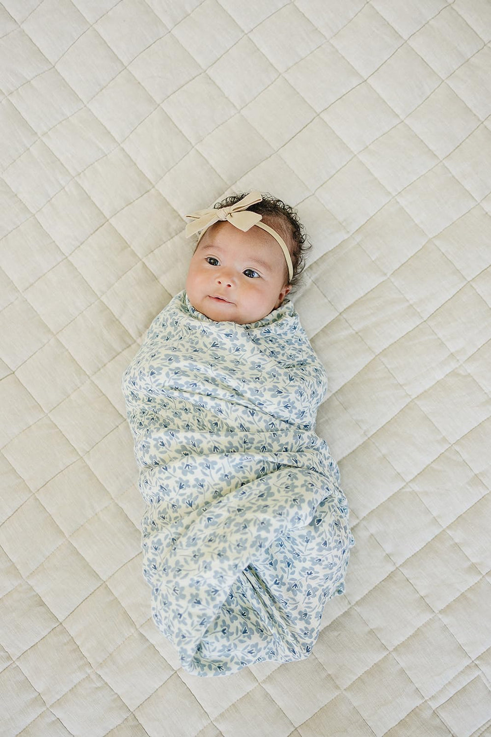 Mebie Baby Blue Blossom swaddle wrapped around baby for secure, cozy sleep