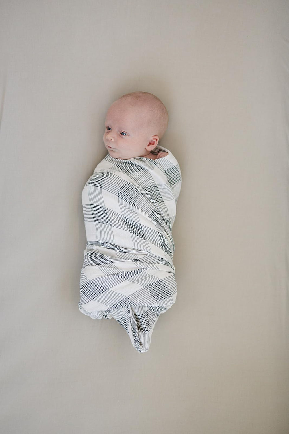 Mebie Baby Coastal Plaid Swaddle on a baby demonstrates a cozy, breathable wrap.