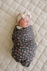 Mebie Baby Olive Bloom swaddle on baby demonstrates secure, comfortable wrap for peaceful sleep.