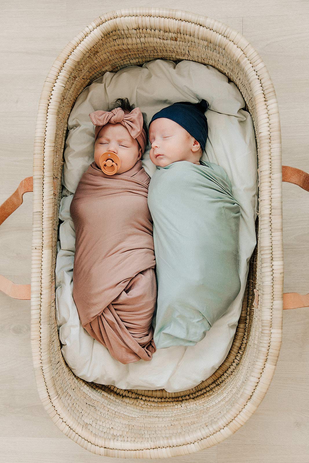 Mebie Baby Sage stretch swaddle shown in nursery coordinates with outfits