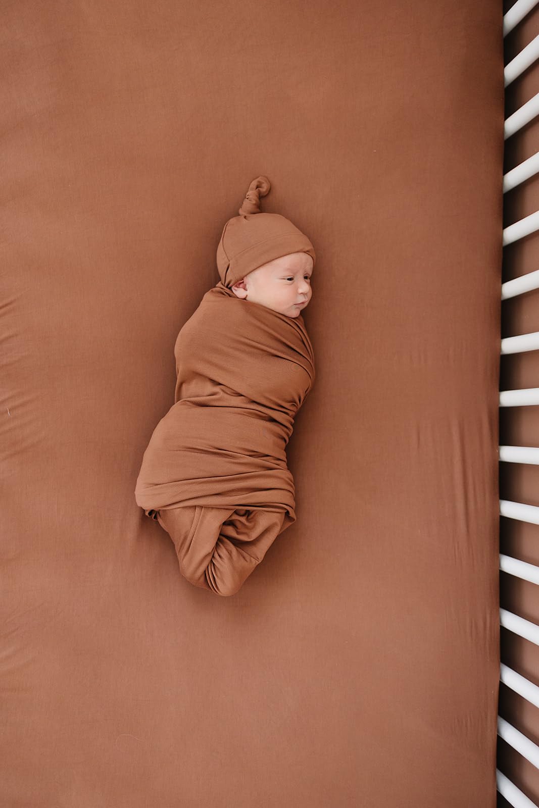 Mebie Baby stretch sheet rust flat lay highlights color versatility for nursery.