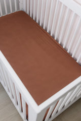 Mebie Baby stretch sheet rust on bed demonstrates secure, stretch-to-fit design.