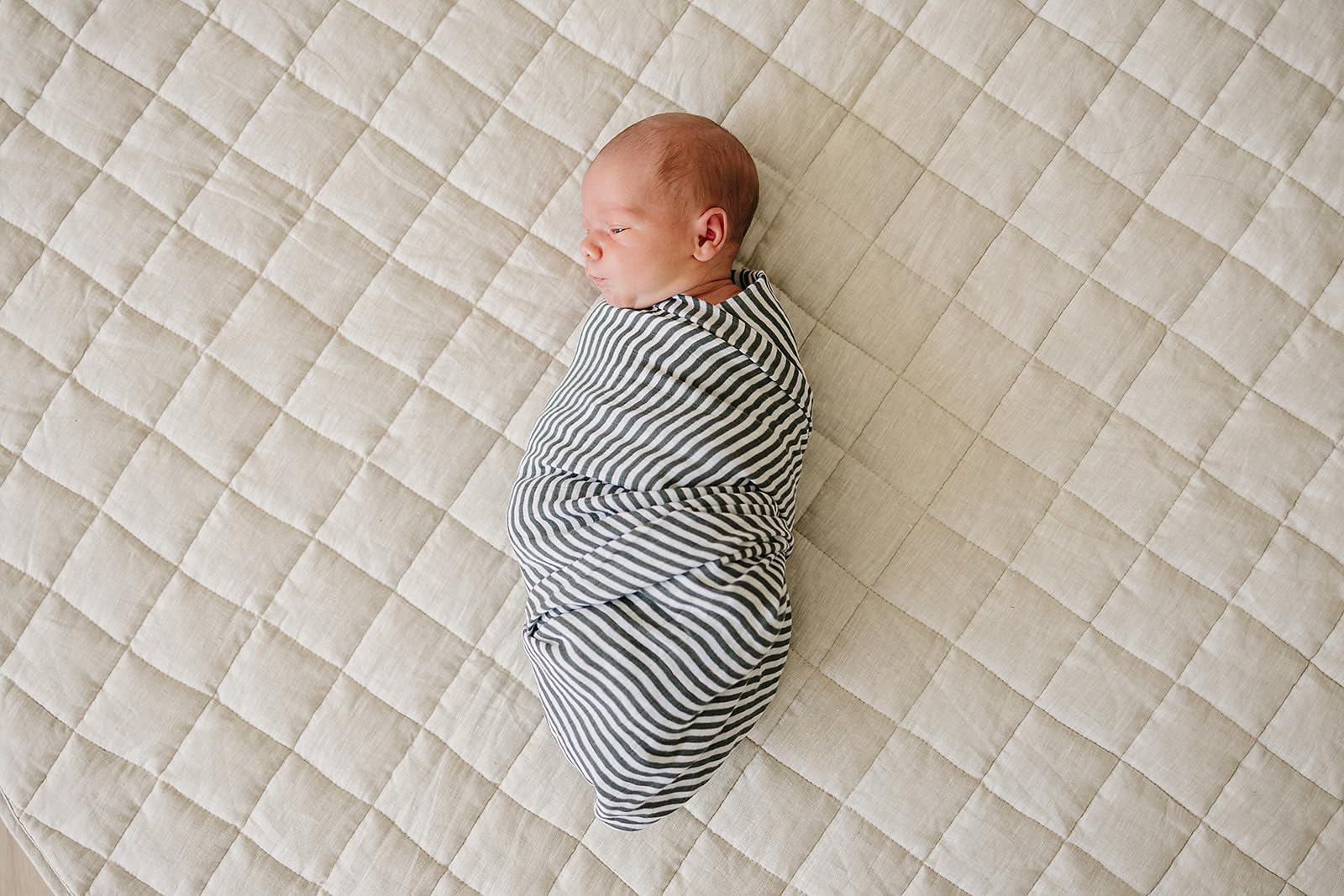 Mebie Baby Vintage Green Stripes swaddle folded in a nursery for easy layering.
