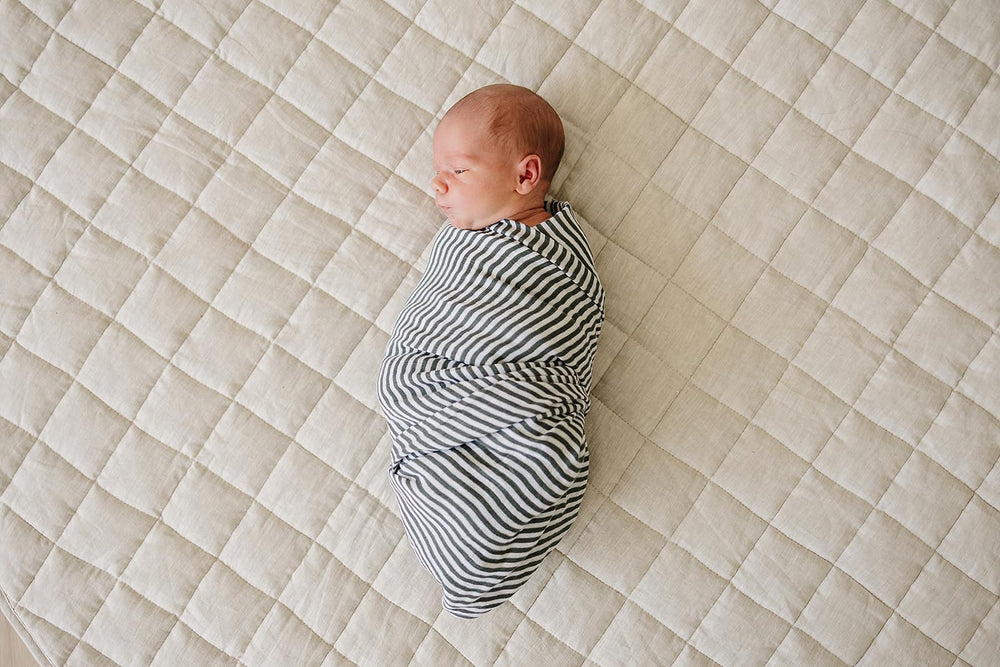 Mebie Baby Vintage Green Stripes swaddle folded in a nursery for easy layering.