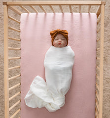 Meracorallo muslin crib sheet pink folded neatly for storage.