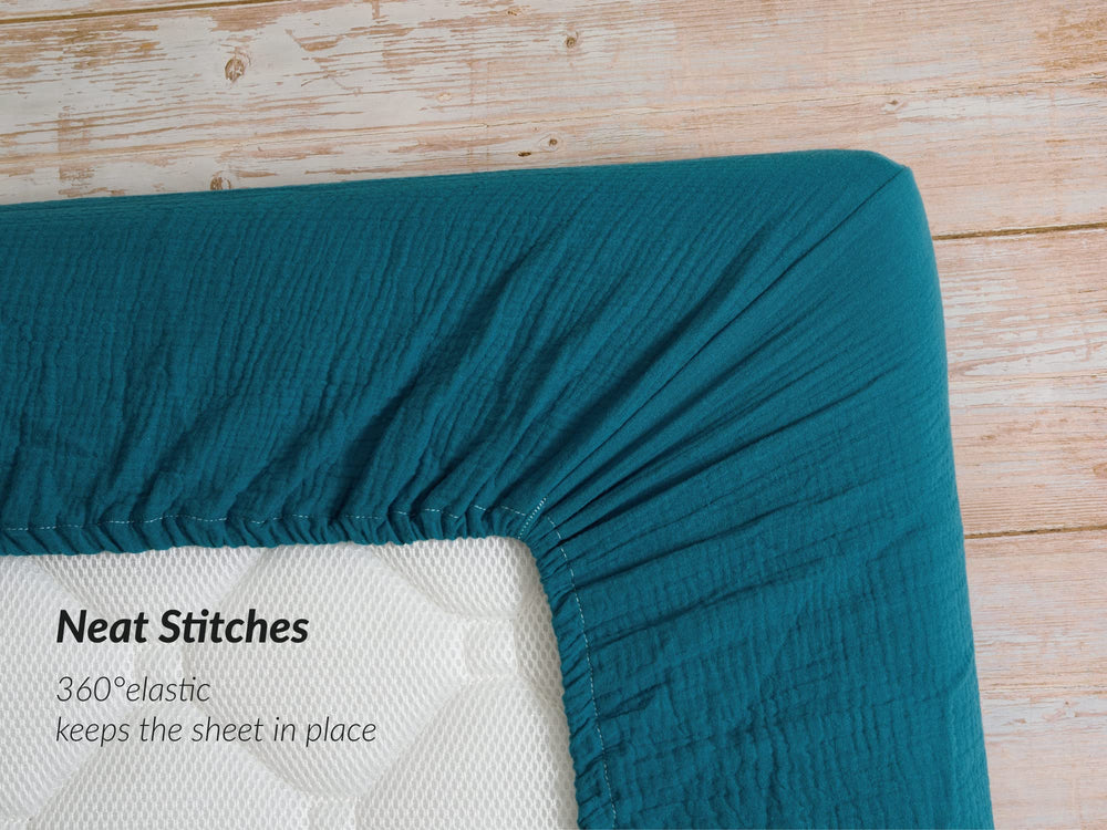 Meracorallo teal muslin sheet shown on standard crib and toddler mattress